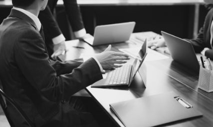 会議室でノートパソコンを前に意見交換をするビジネスパーソンの様子