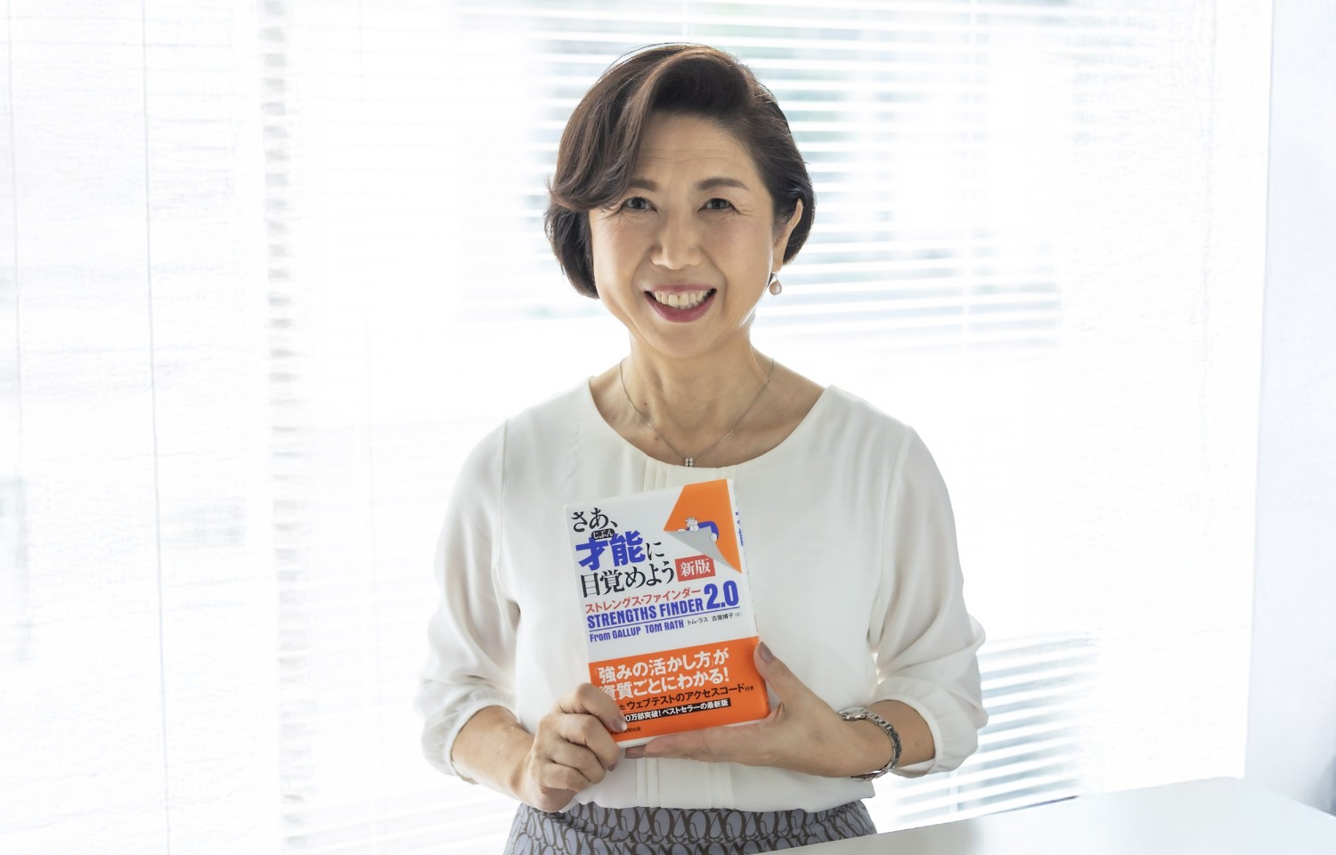 本を持って微笑む丹羽コーチ