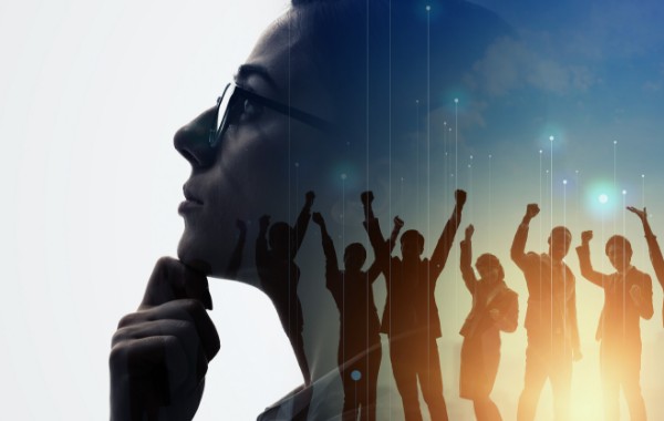 考える女性の背景に、手を上げて喜んでいるチームメイトのシルエット