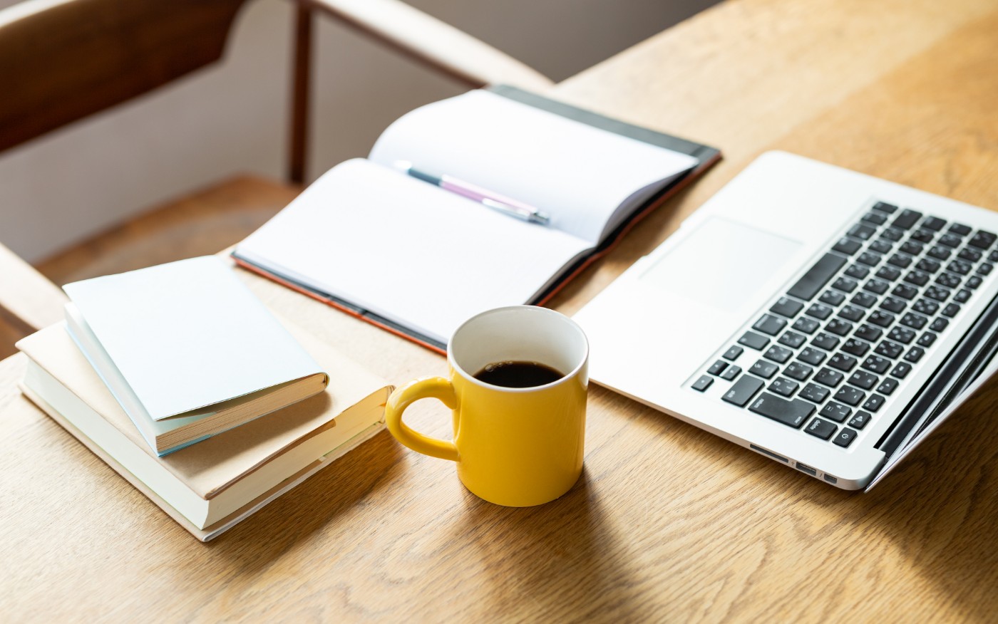 デスク上に、コーヒー、PC、本が置いてある様子